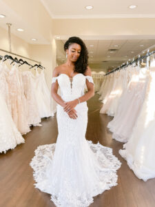 Petite bride wears a removable off the shoulder lace fitted wedding dress with curved sparkle detail