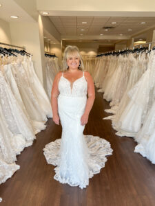 Mid size bride wears an ivory allover lace fitted wedding dress with a deep v neckline and spaghetti straps