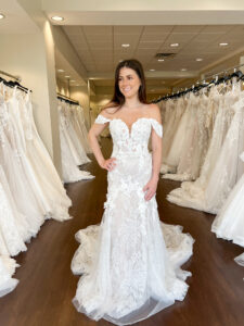 Brunette brides wears a mermaid wedding dress with removable off the shoulder straps and large 3D floral elements