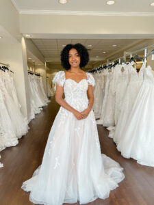 bride with natural curls wears a flutter sleeve soft ballgown in a blush color