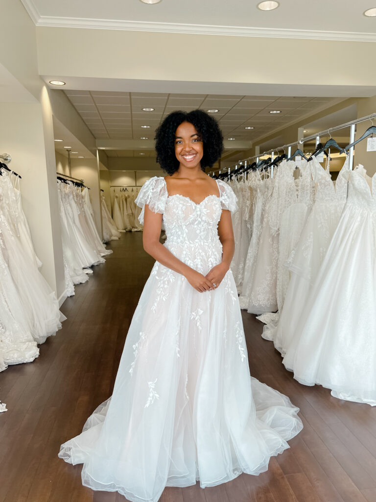 Bride with natural hair wears a soft aline wedding dress with flutter sleeves and 3D leaf lace throughout the sleeves, bodice and skirt.