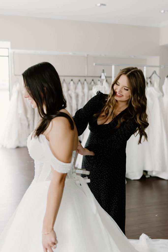 One Fine Day bridal consultant helping a bride into a wedding dress